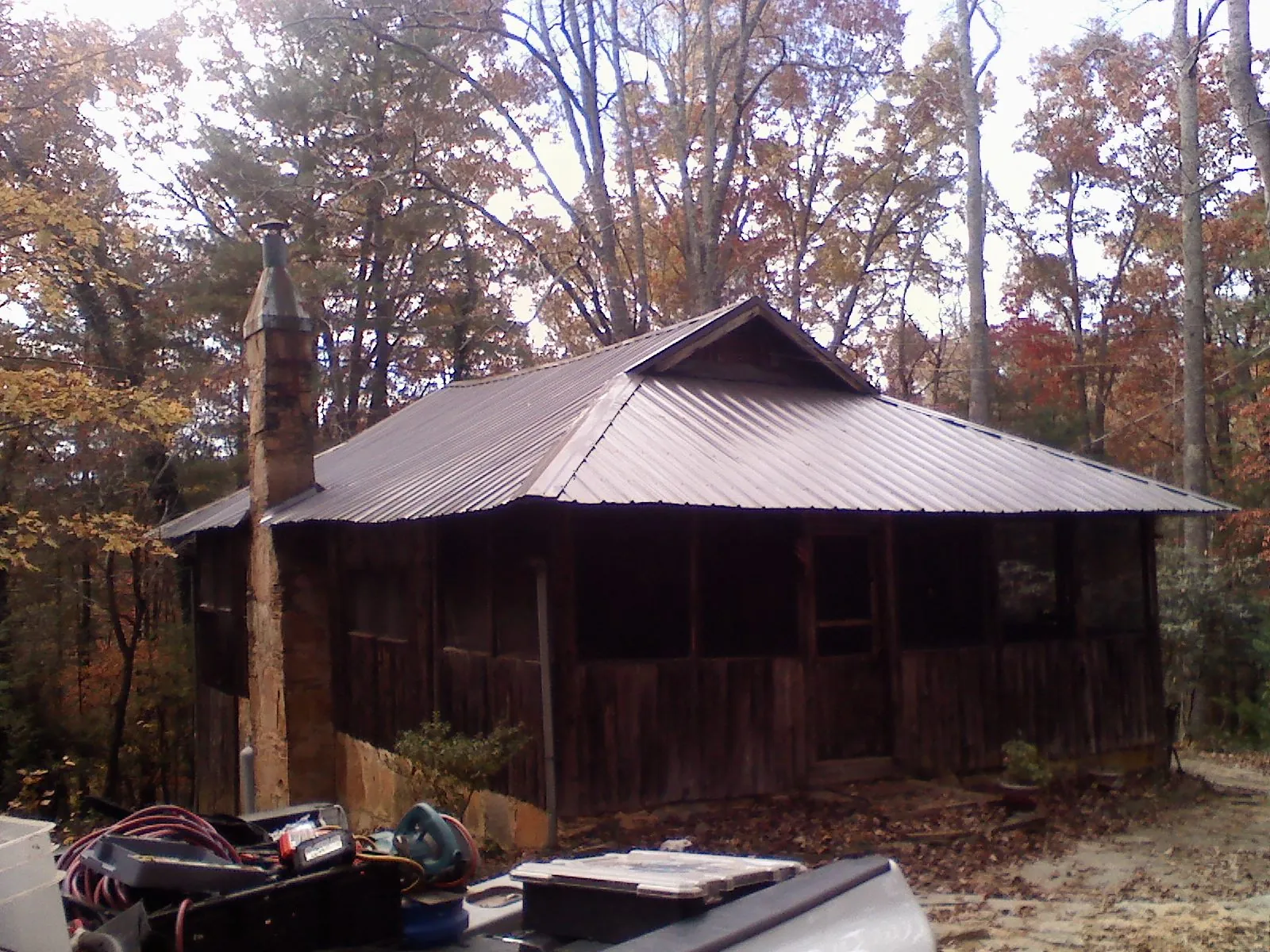 Brown metal hip roof on an old cabin with a stone chimney in Williamsport